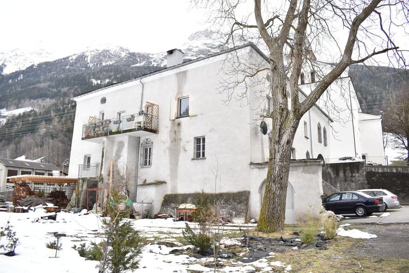 3 story white house, balcony, snow, large tree in front, 2 cars parked