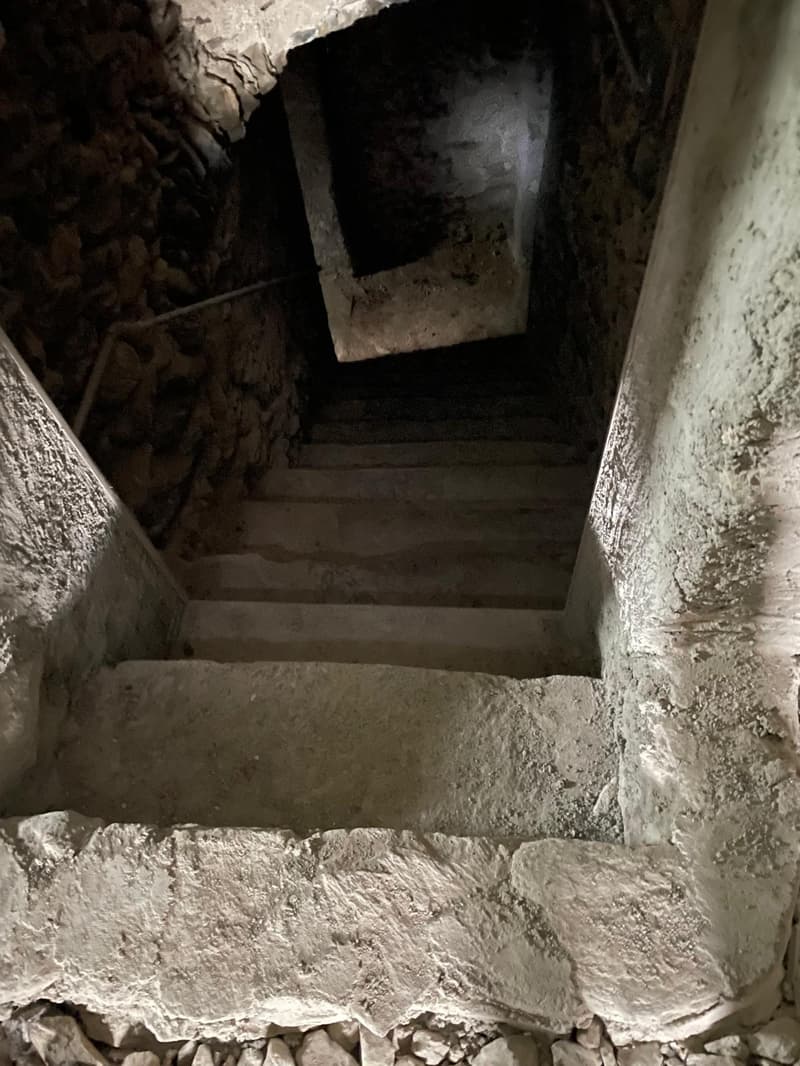 concrete stairs leading to an underground room, stones in the sides, open doorway