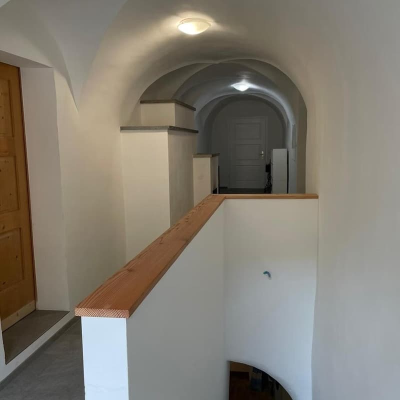 vaulted ceiling, wooden floor, wooden railings, white walls, arched door