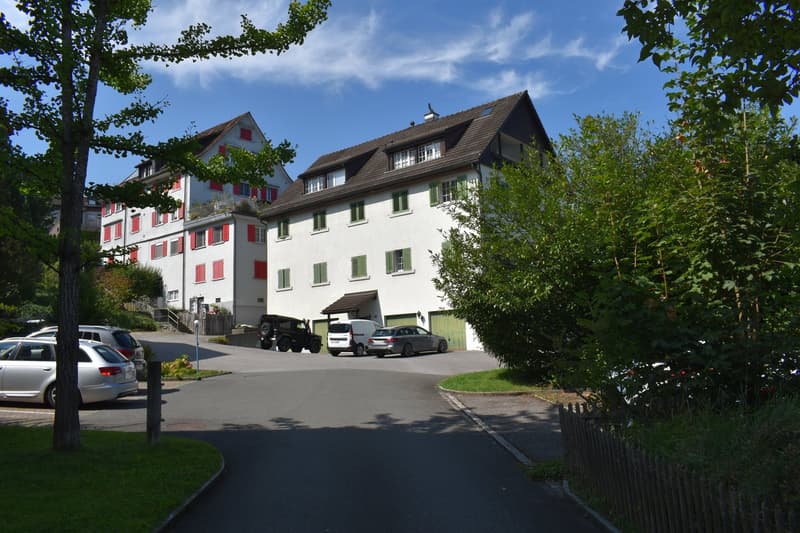 2 story building, white exterior, red shutters, brown roof, multiple cars parked in front