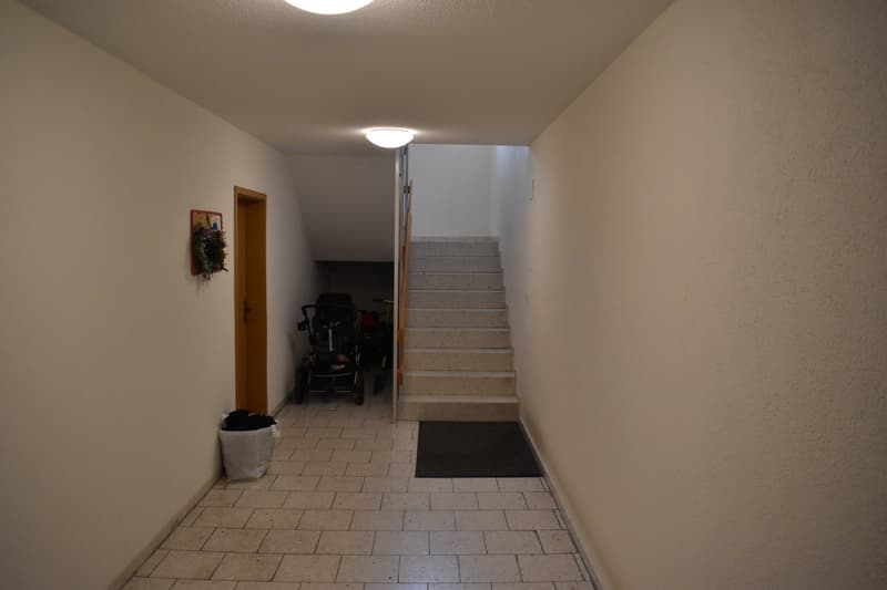 tiled floor, white walls, light on ceiling, stairs, door, trash bin, picture frame
