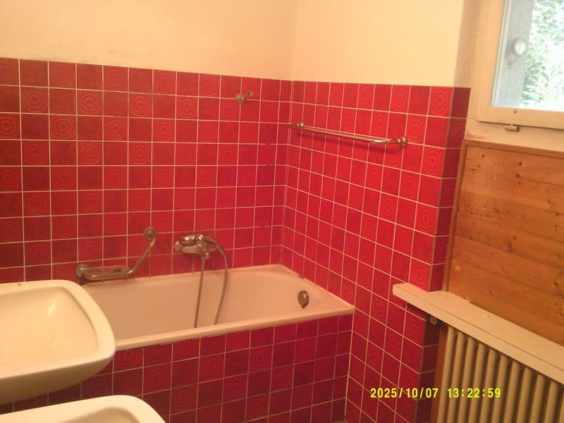 Bathroom with red tiles, white bathtub, white sink, silver faucet, wooden wall, window