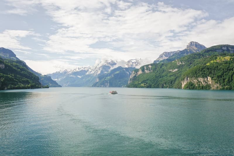 A serene lake with a boat in the middle, surrounded by mountains and a cloudy sky.