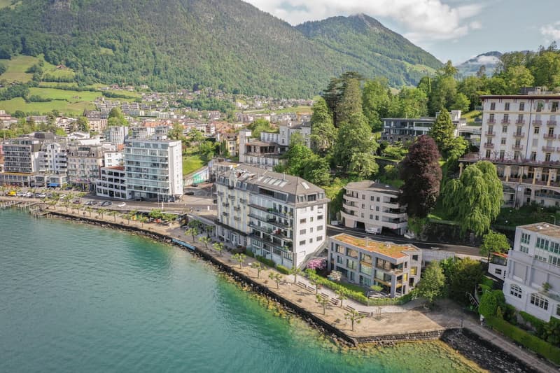 Aerial view of a town with buildings, mountains, and a lake in the background
