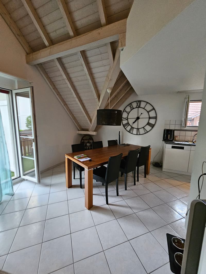white ceiling, wooden beam, dining table with 6 chairs, kitchen counter, large clock on wall
