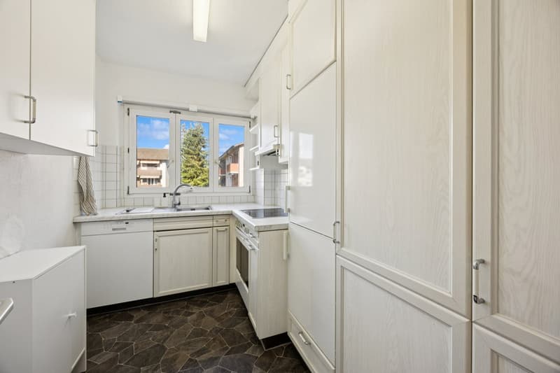 Modern clean kitchen with white cabinetry, tiled backsplash, countertop, built-in oven, and integrated dishwasher.