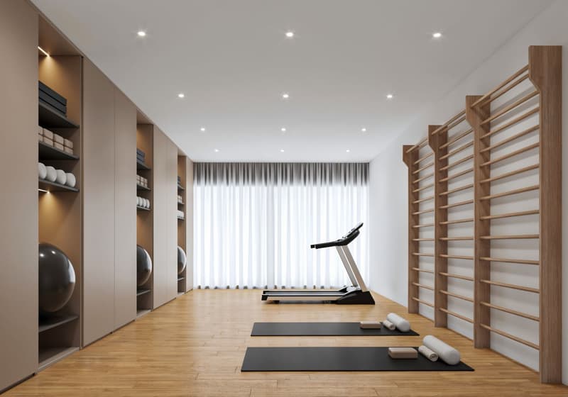 A room with a treadmill, yoga mats, exercise balls, and wooden racks with shelves