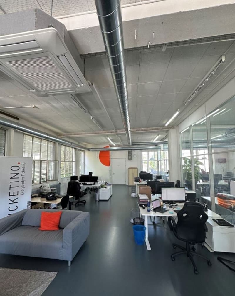 modern office space with desks, computers, glass walls, windows, grey floor