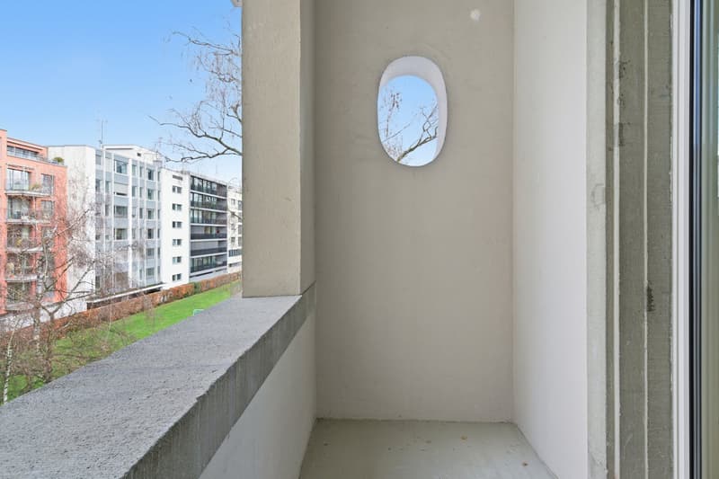 Balcony with concrete railing, white walls, oval window, concrete floor
