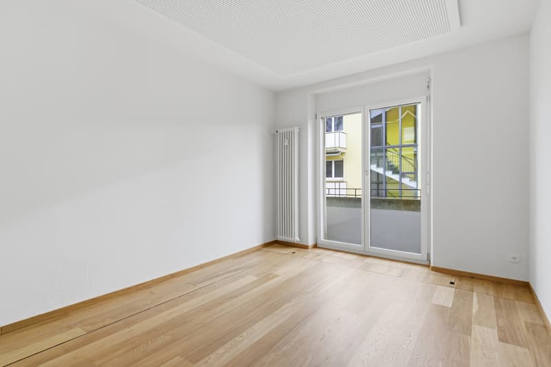empty room, wooden floor, white walls, sliding glass door, balcony, radiator, power outlet