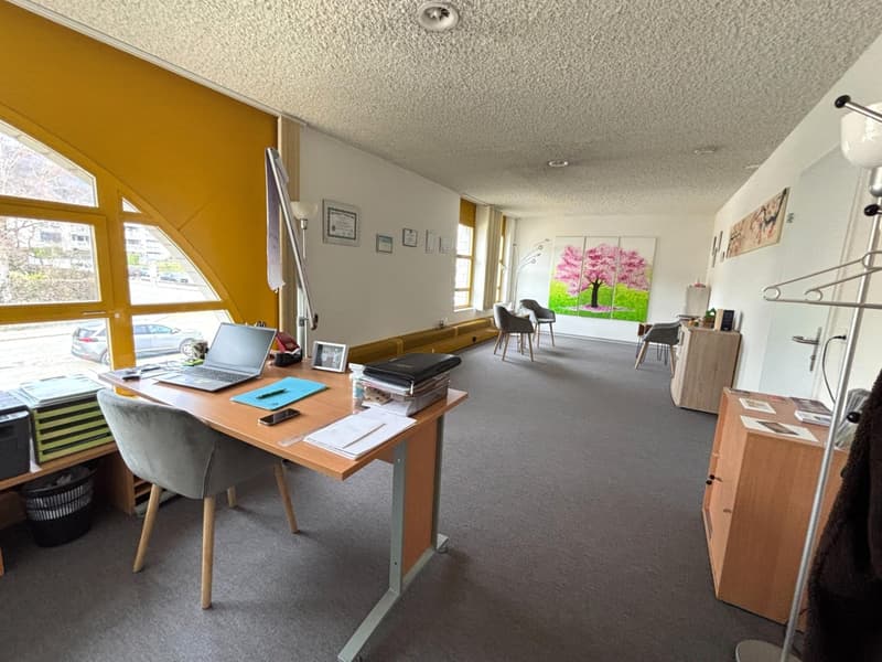 Office room with desk, chair, laptop, picture frames, cabinets, and large windows