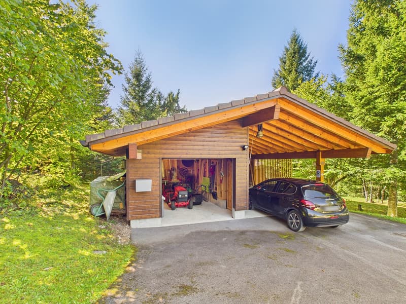Detached wooden garage, car parked inside, storage equipment and machinery in the garage.