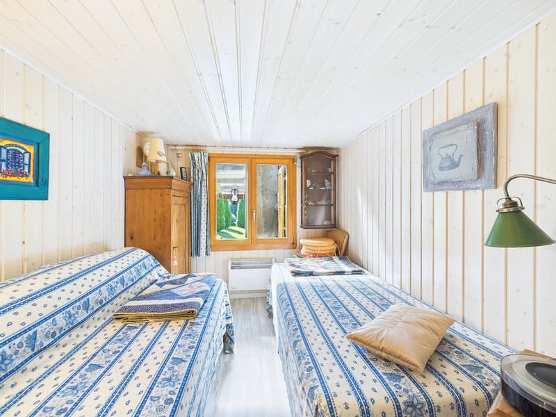 bedroom with two beds, wooden cabinet, radiator, window, lamp, paintings