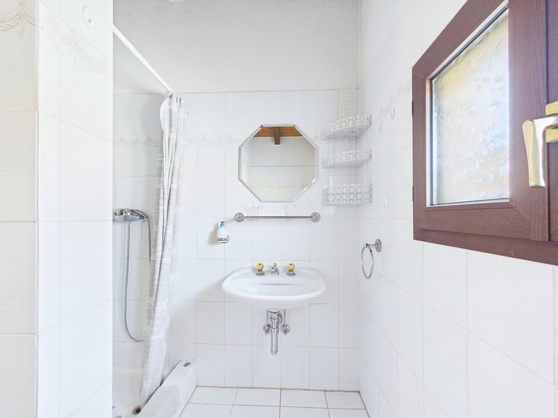 Bathroom with white tiles, shower, sink, mirror, and shelves