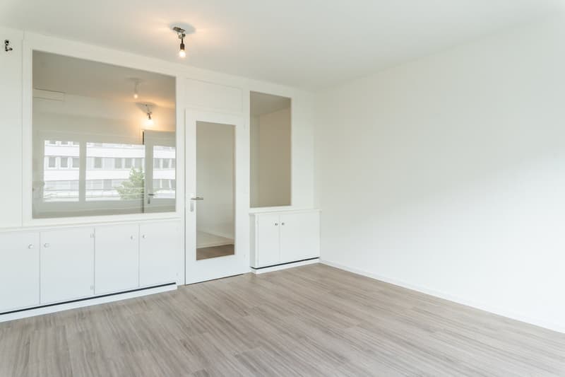 empty room, white walls, wooden floor, white cabinets, glass door, mirror, ceiling lights
