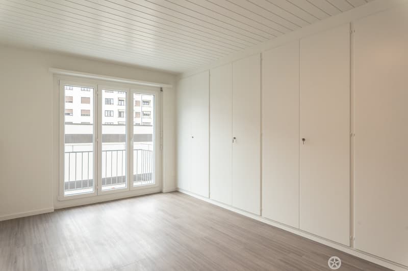 empty room, wooden floor, sliding glass doors, balcony, white walls, built-in wardrobes