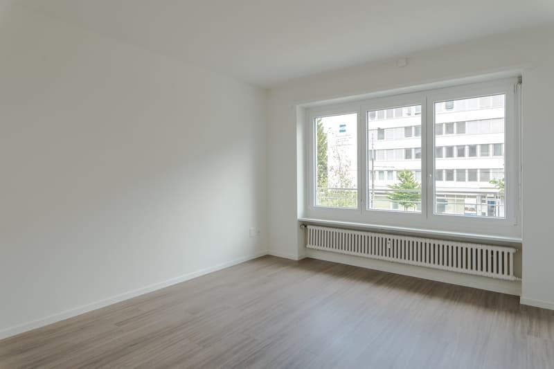 empty room, white walls, wooden floor, large windows, white radiator