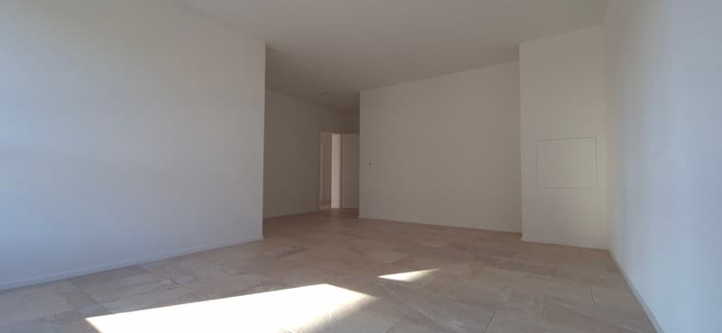 Empty room with white walls, tiled floor, and an open door leading to another room.