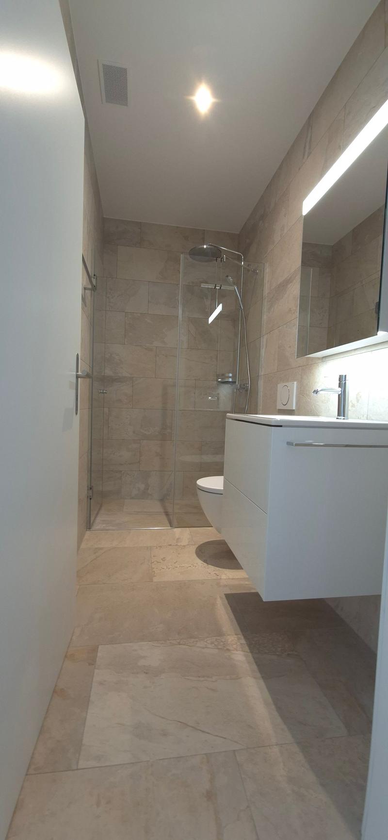 modern bathroom with glass shower, white sink, beige tiles, white toilet, mirror