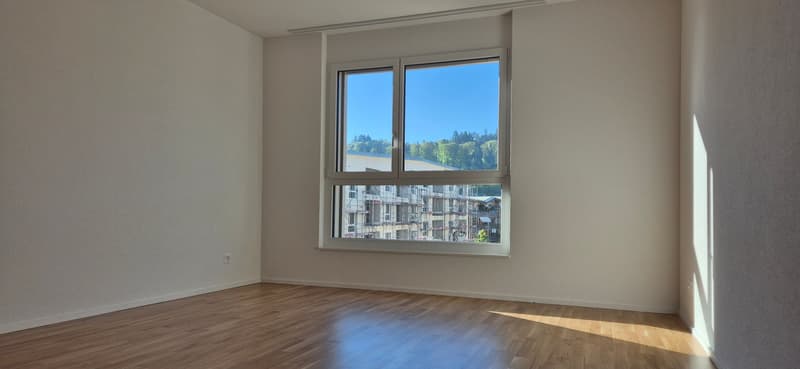 empty room, wooden floor, white walls, large window, view of trees and buildings