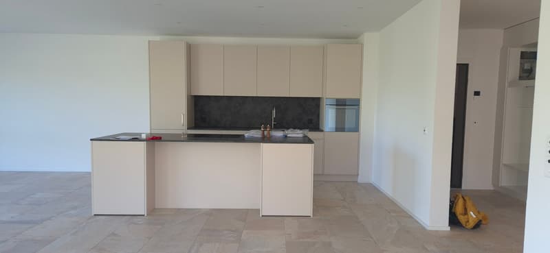 modern kitchen with island, white cabinets, black countertops, stainless steel faucet, built-in oven, tiled floor