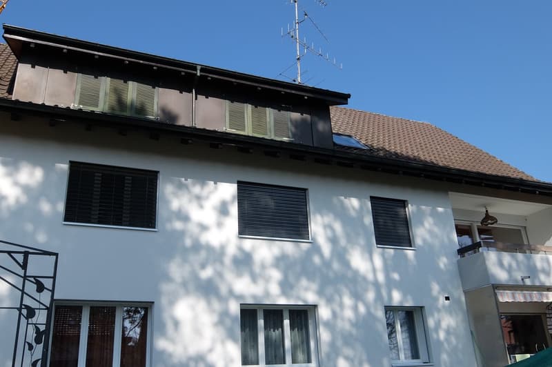 white exterior, brown roof, multiple windows, balcony, solar panel on roof