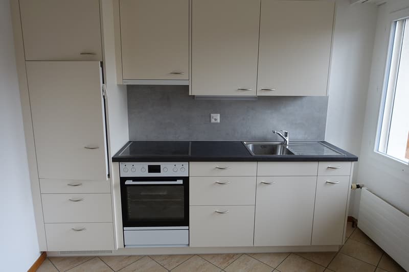 Modern kitchen with white cabinets, black countertop, built-in oven, and dishwasher