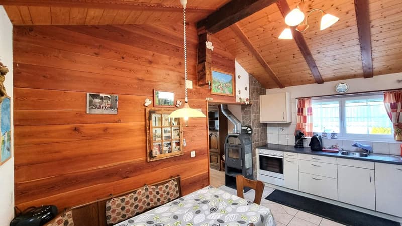 Cozy wooden cabin-style kitchen with a wood-burning stove, built-in cabinets, and a dining area with a patterned tablecloth