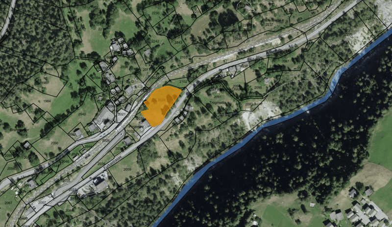 This is a map showing a rural area with a river running through it. There are several buildings and roads visible, as well as a large yellow-highlighted area that appears to be a parking lot or similar facility.