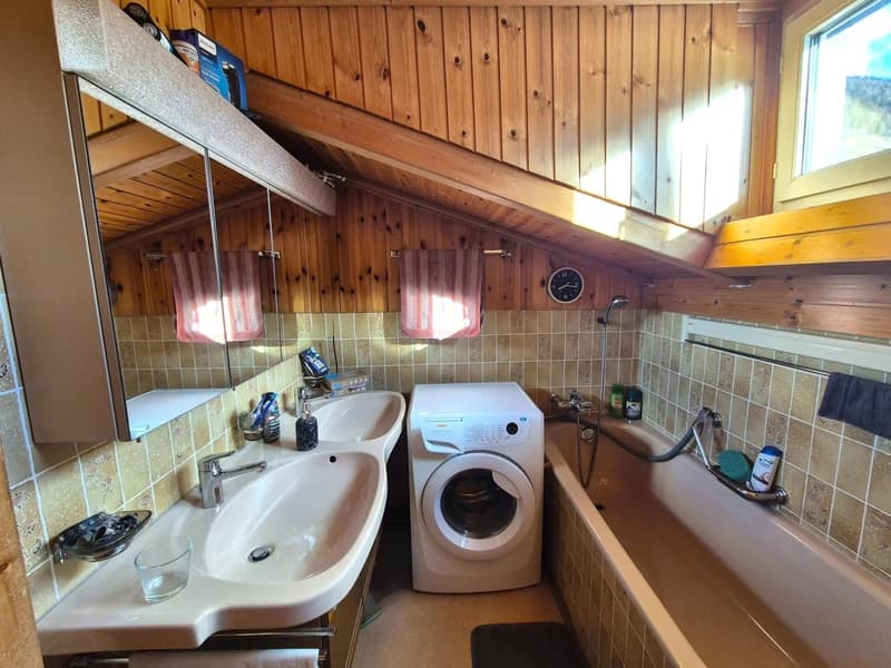 Bathroom with wooden walls, double sink vanity, washing machine, and tiled floor