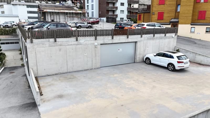 Concrete garage with parking spaces, surrounded by residential buildings