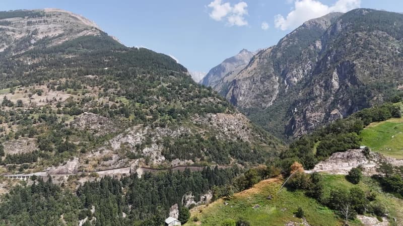 Valley with mountains, lush vegetation, a small house, a railway in the valley.