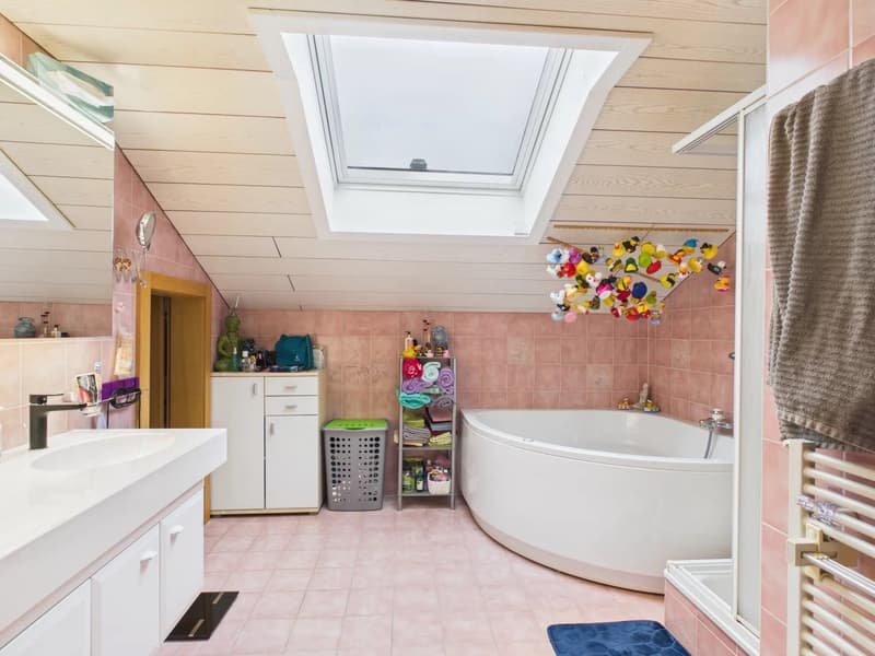 Bathroom with bathtub, sink, skylight, tiled floor, towel rack, cabinet, laundry basket, decorative objects
