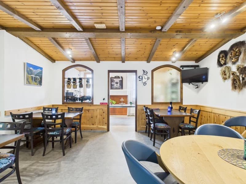 Wooden dining room with tables and chairs, large clock, TV, framed painting, wooden walls, wooden ceiling