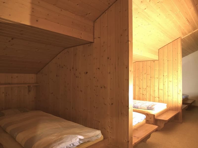 wooden walls, single bed with mattresses, wooden bed frames, wooden bench, wooden shelves, slanted ceiling
