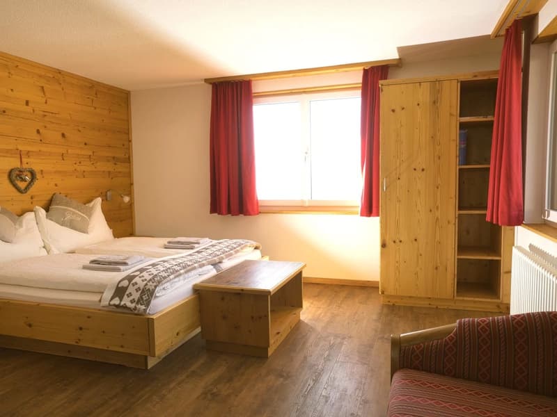 Wooden wall, bed, wooden nightstand, wooden bench, wooden cabinet, radiator, curtains