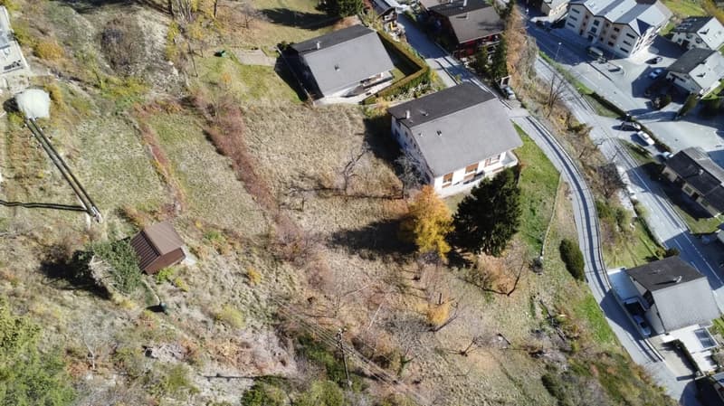 Empty plot of land with surrounding houses and a road.