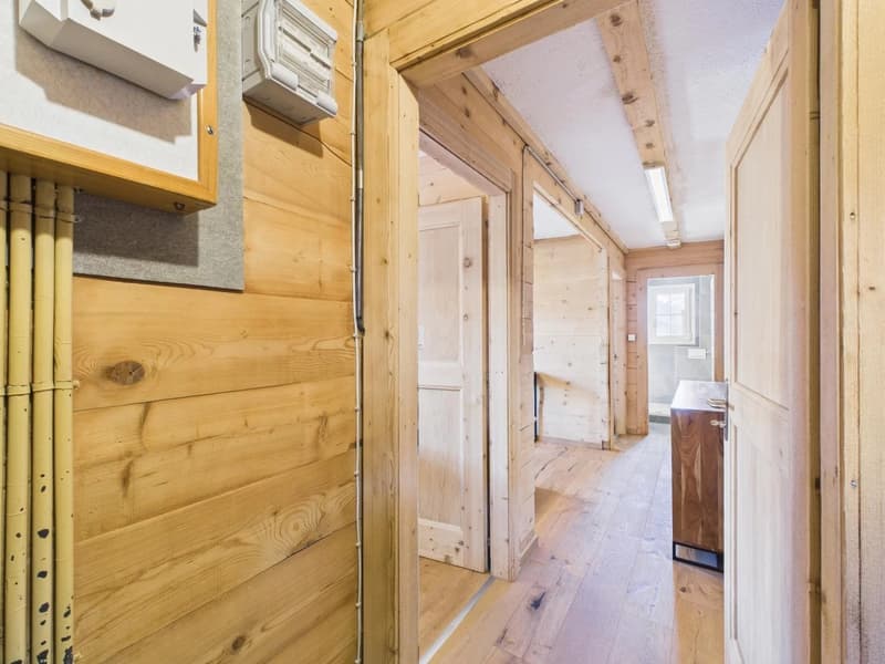 wooden walls, wooden floor, small hallway leading to two rooms