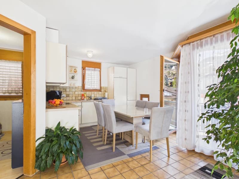 dining room with table, chairs, kitchen area with cabinets, fruits bowl, tiled floor, white walls, curtains, wooden floor