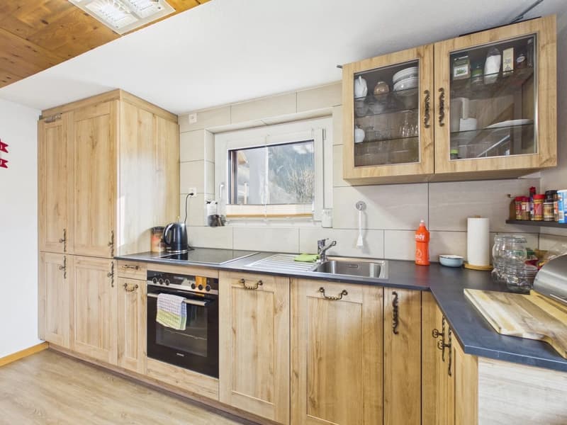kitchen with wooden cabinets, black countertops, sink, oven, stove, windows, natural light