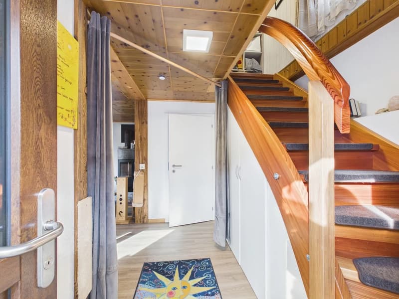 Wooden stairs, wooden handrail, light in ceiling, rug on the floor, doors, yellow paper on the wall