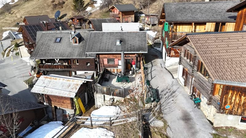 Collection of wooden chalets in a village, solar panels, snow cover, driveway, garden, fencing