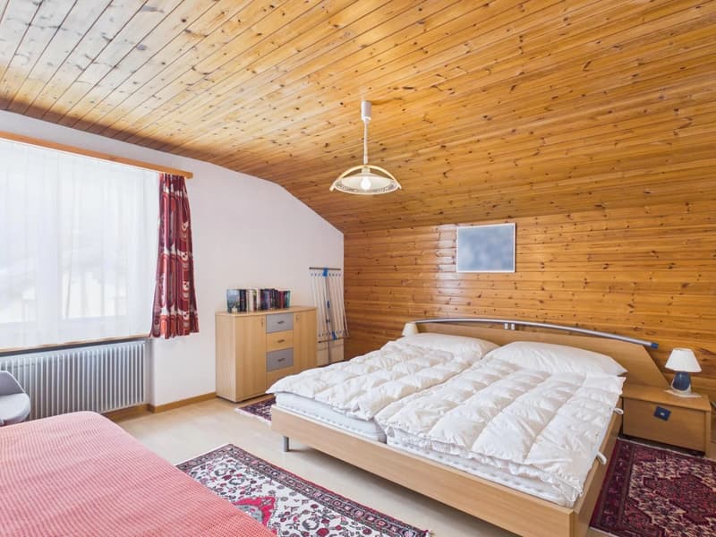 bedroom with wooden walls, bed, nightstands, cabinet, radiator, rug, lamp, books