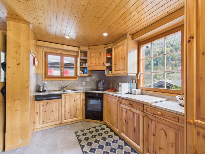 kitchen with wooden cabinets, granite countertops, black oven, sink, dishwasher, large window with view
