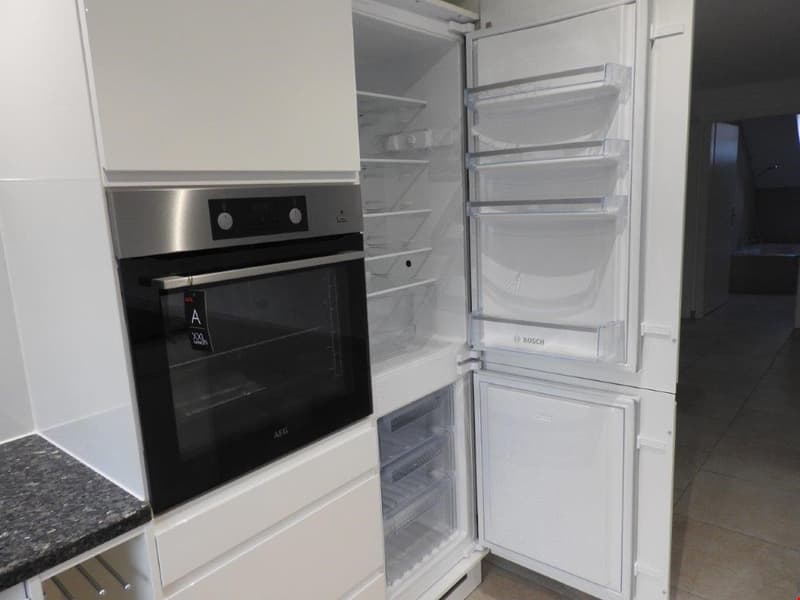 modern kitchen with white cabinets, stainless steel oven, refrigerator, granite countertop