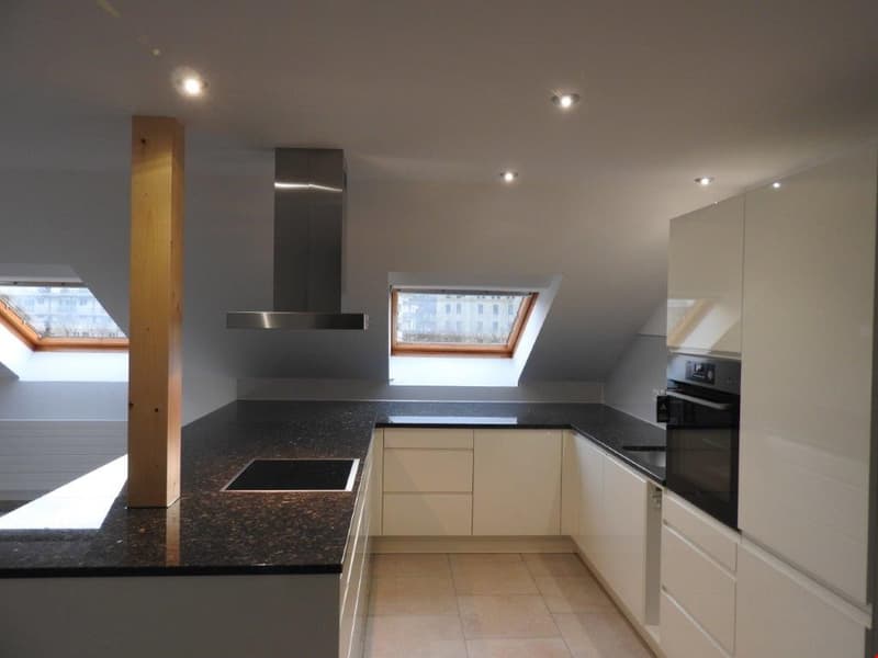 modern kitchen with granite countertops, stainless steel appliances, white cabinets, skylights, wooden column