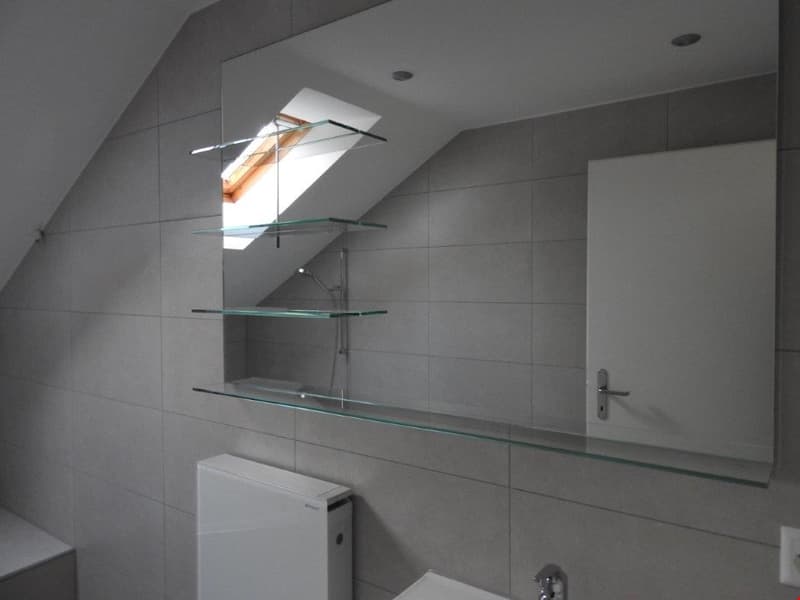 Bathroom with glass shelves, mirror, white tiles, skylight, white sink, white toilet