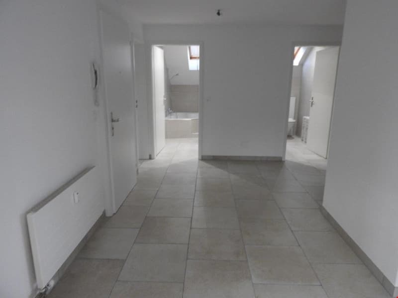 Empty hallway with tiled floor, white walls, and doors leading to bathroom and bedroom