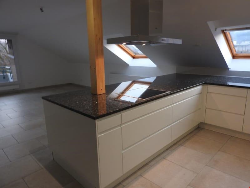 modern kitchen with island, granite countertops, white cabinets, wooden pillar, skylights