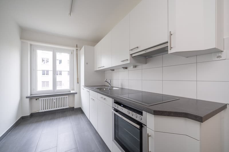modern kitchen with white cabinets, gray tiled floor, stainless steel appliances, window with view